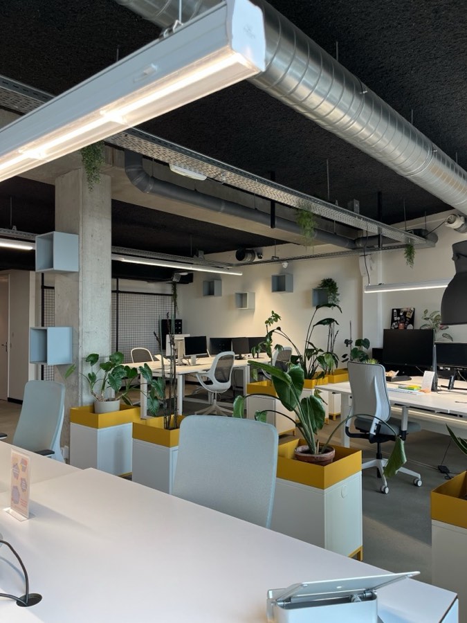 Flexplekken met witte bureaus en planten in gele bakken bij De Kaapstander in Nijmegen